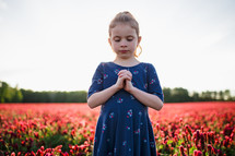 a praying girl in a field of flowers 