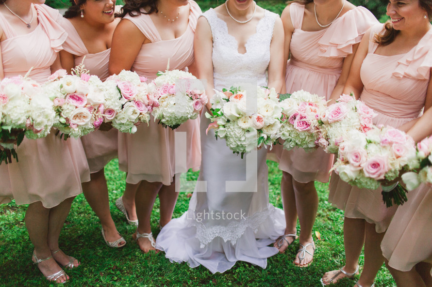 torsos of bride and bridesmaids holding bouquets 