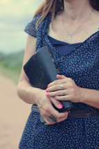 woman holding a Bible standing on a dirt road 