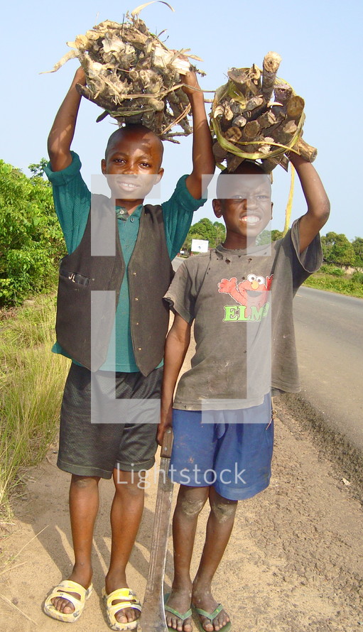 Children carrying bundles of sticks on their heads 