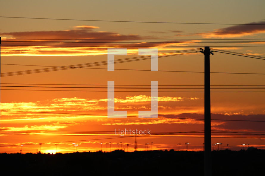 power lines under an orange sky at sunset 