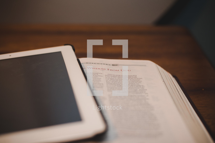 a tablet on the pages of a Bible 