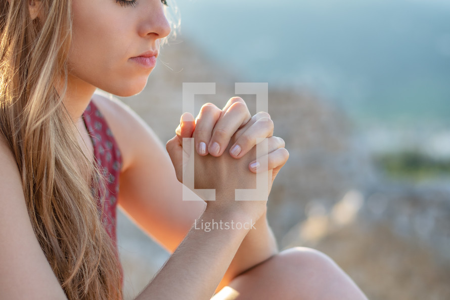 a young woman praying outdoors