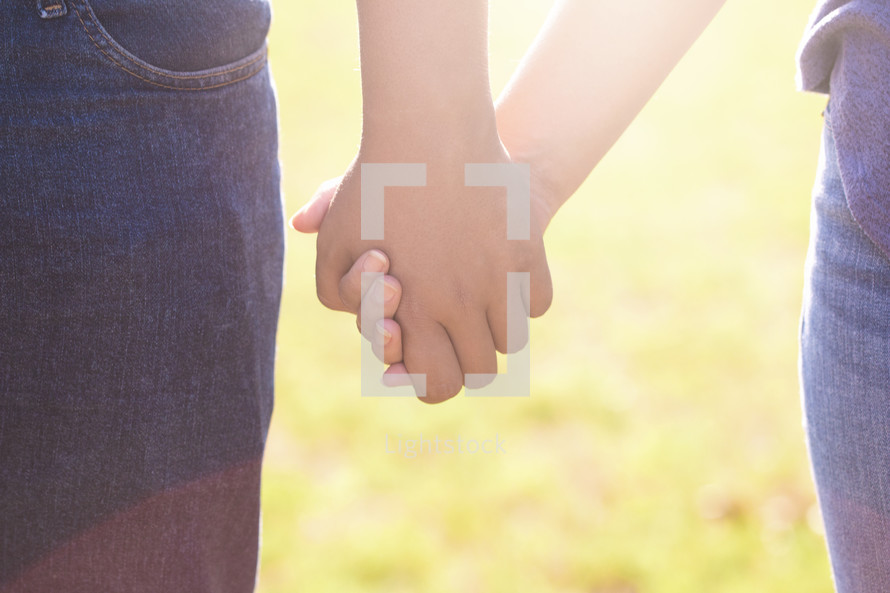 A Young Man and Woman Holding Hands Outside in the Sun