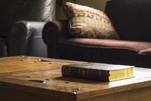 pillow and couch and a Bible on a coffee table 
