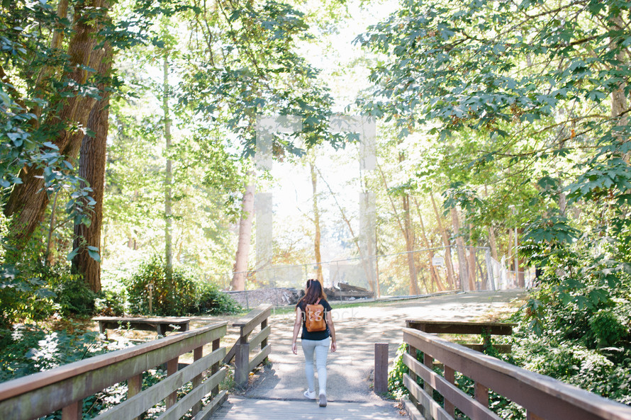 a woman with a backpack walking in a park 