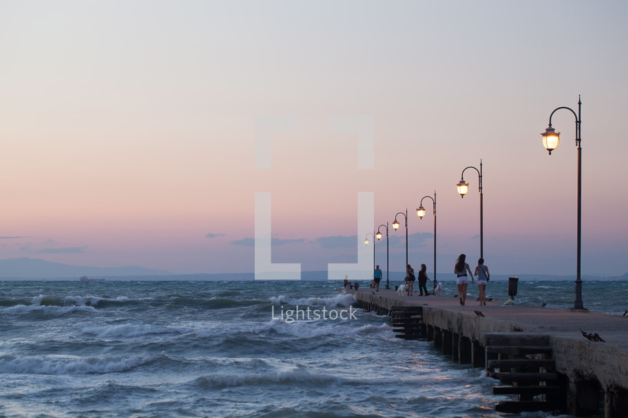 People walking along the pier in evening