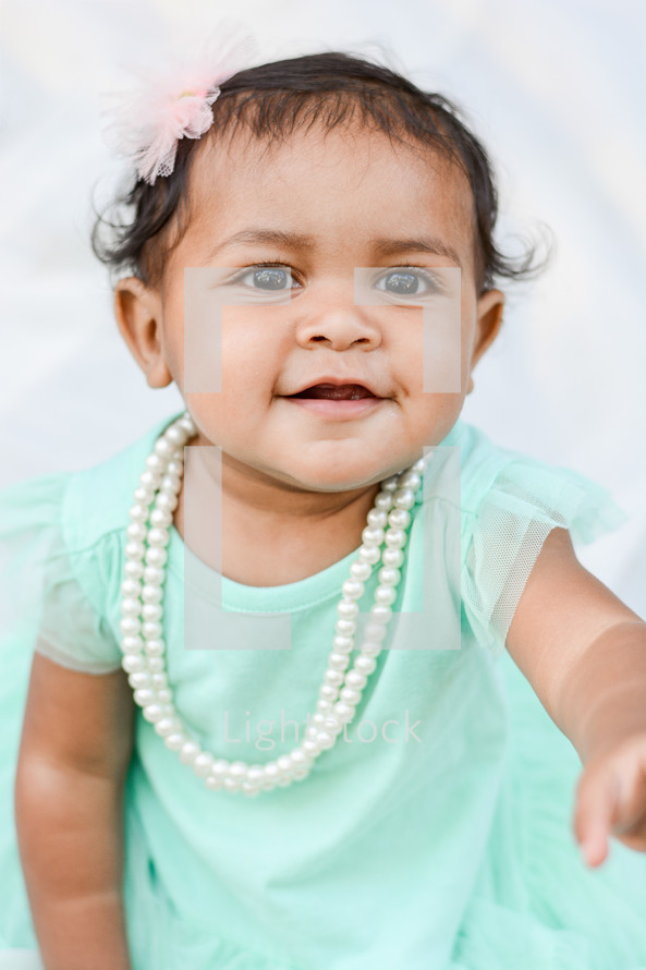 a toddler girl in pearls 