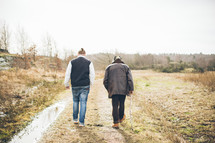 two men walking down a dirt path 