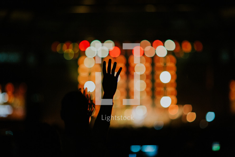 raised hands at a concert and bokeh lights 