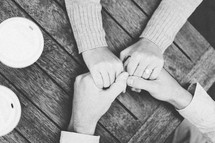 couple holding hands on a wood table 