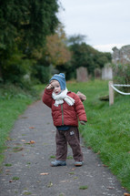 a boy toddler walking on a path to a cemetery 