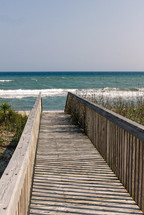 Wooden walkway with rails leading to beach.