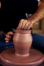 A man molding a pot on a potter's wheel