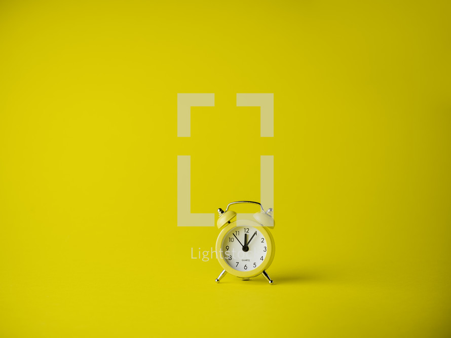 Yellow alarm clock over a yellow background