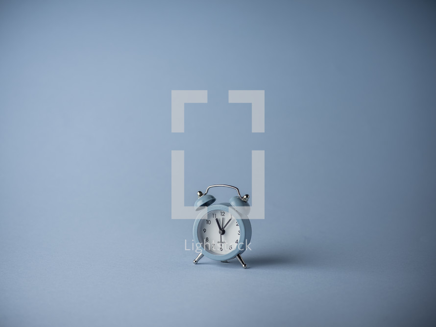 Blue alarm clock over a turquoise background
