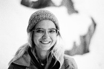 smiling face of a woman with glasses wearing a beanie 