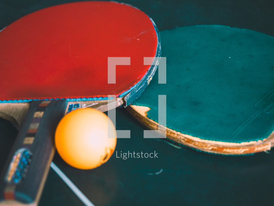 two ping-pong bats and a ball on a table tennis table