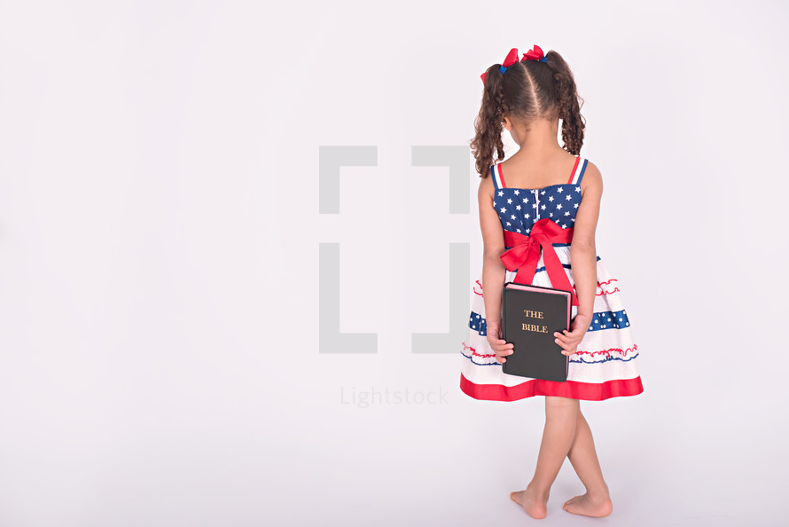 girl child holding a Bible behind her back 