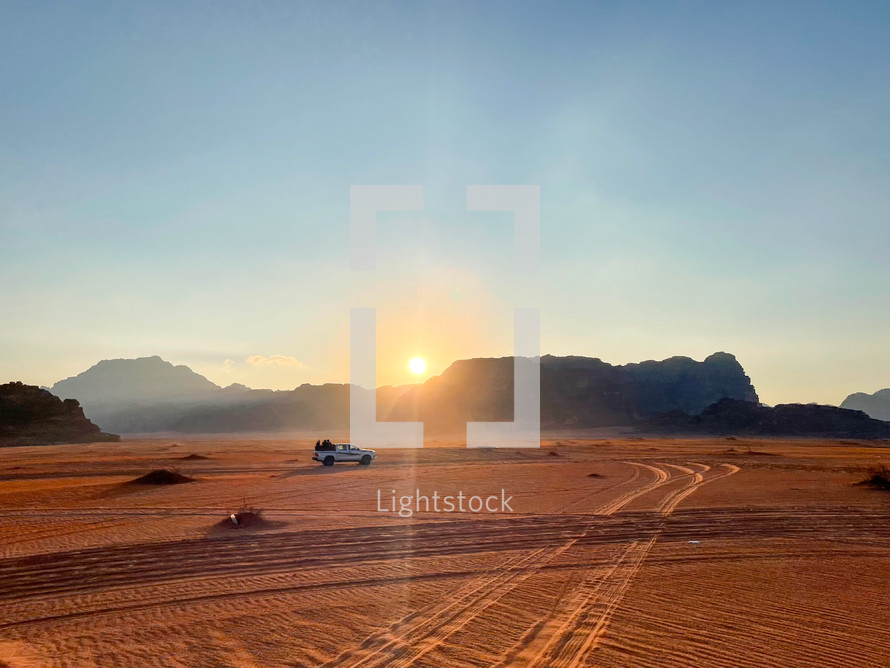 Safari in Wadi Rum desert, Jordan, Middle East. Tourists in the car ride on off-road on sand among the beautiful rocks at sunset.