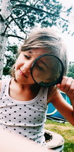child looking through a magnifying glass 