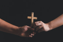 Two people holding a wooden cross