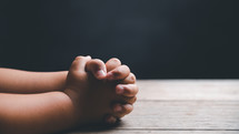 Small child's hands clasped in prayer