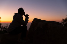 Woman kneeling in prayer at sunset