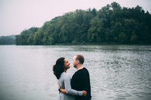 a couple hugging by a lake shore 