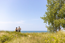 view of large body of water framed by a tree and a couple gazing in the distance