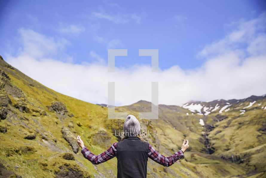 a woman with arms raised with Iceland landscape in the background 