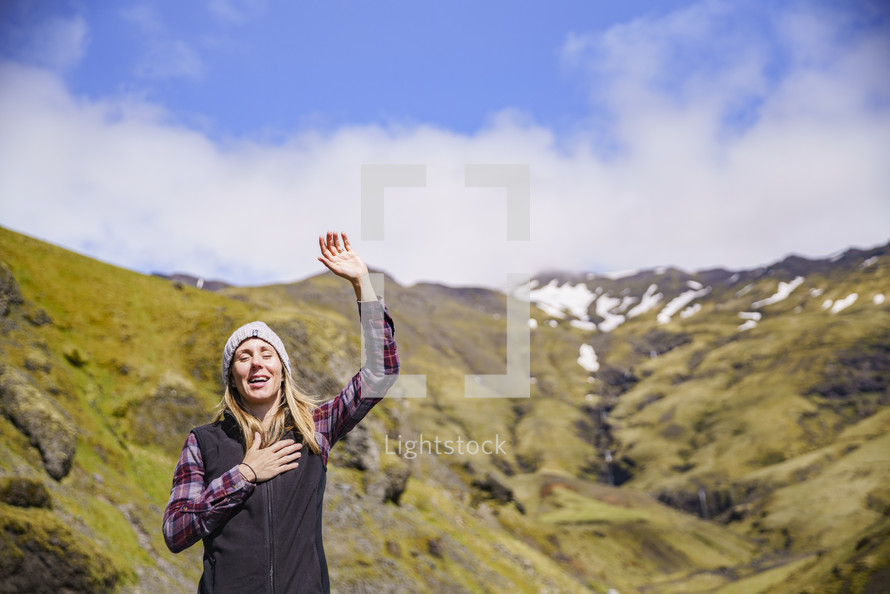  a woman standing outdoors with hands raised in Iceland 