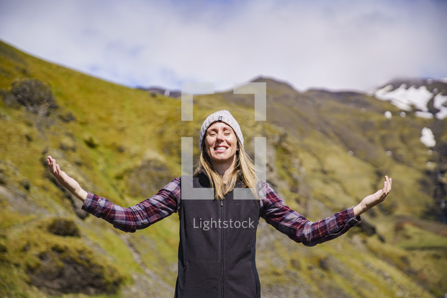 a woman standing outdoors with hands raised in Iceland 