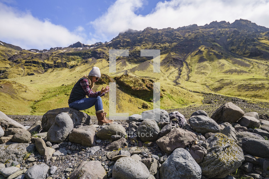 A woman sitting on a rock praying in Iceland 
