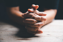 Person's hands clasped in prayer