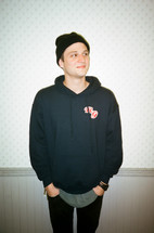 a man with hands in his pockets wearing a sweatshirt and beanie 