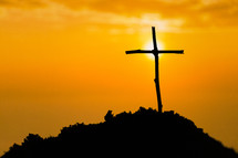 Wooden cross on a hill with a vivid sunset background