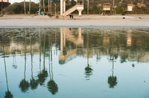lifeguard stands and reflection of palm trees and calm water 