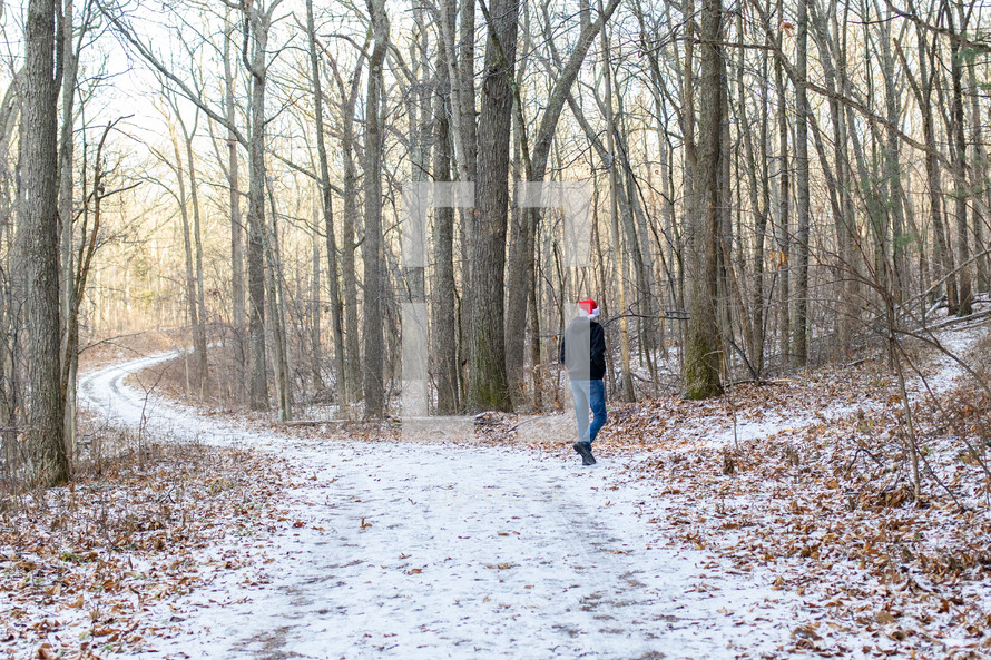 a man in a Santa hat walking on a snowy path 