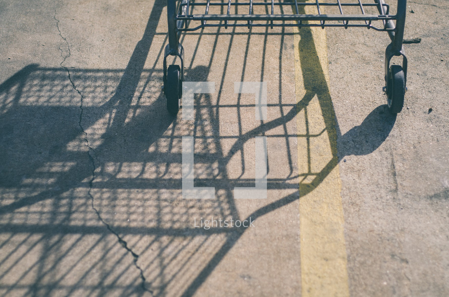Shadow of a grocery cart reflected on an asphalt road