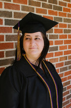 graduate in front of a brick wall