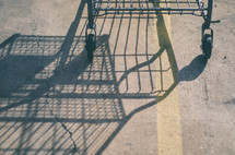 Shadow of a grocery cart reflected on an asphalt road