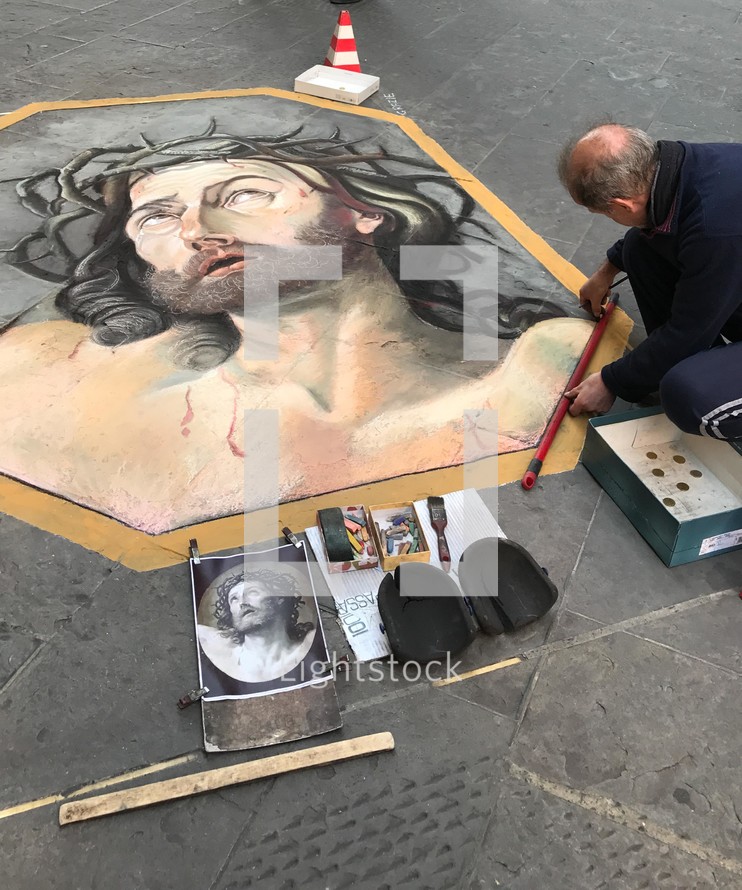 street artist painting Jesus on a sidewalk