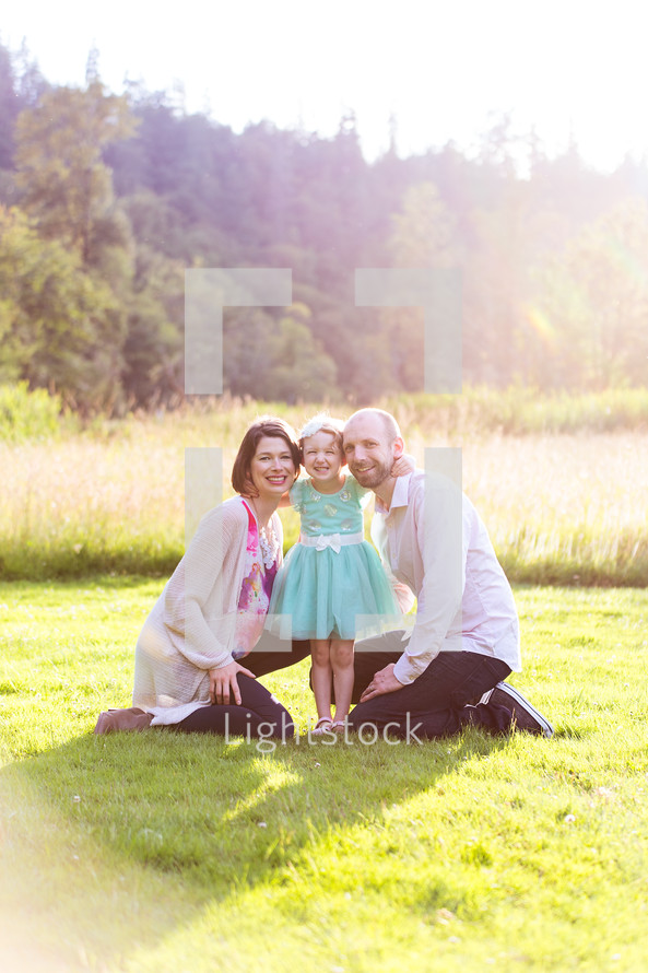 portrait of a family sitting in grass outdoors 