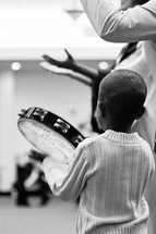 child playing a tambourine at a worship service