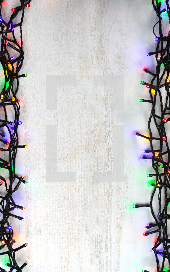 colored Christmas lights border on wood background 