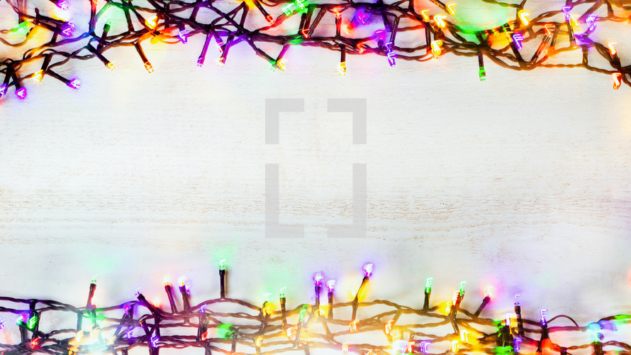 colored Christmas lights on a white wood background 