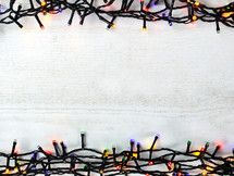 colored Christmas lights on white wood background 