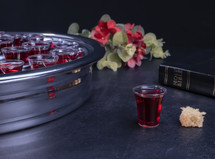 Communion glass cups on tray filled with wine, the symbol of Jesus Christ blood, next to a bible
