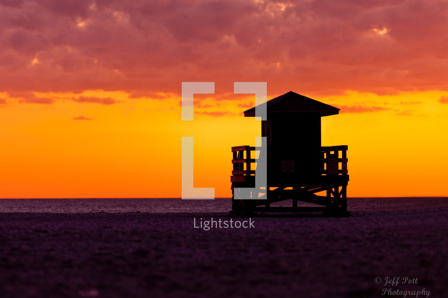 silhouette of a lifeguard stand on a beach at sunset 